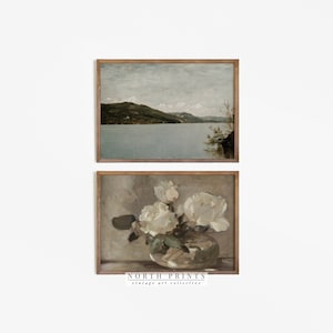 May include: Two framed vintage art prints. The top print depicts a landscape with a lake and mountains under a cloudy sky. The bottom print shows white roses in a glass vase. The text "NORTH PRINTS vintage art collective" is at the bottom.