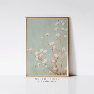 May include: A framed print of a watercolor painting featuring delicate white flowers on a light blue background. The painting has a vintage aesthetic and is titled "NORTH PRINTS art collective".