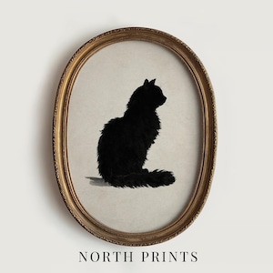 Peut inclure: Une impression encadr&eacute;e ovale repr&eacute;sentant une silhouette de chat noir. Le chat est de profil, avec une apparence duveteuse. Le cadre est dor&eacute; et le fond est beige neutre. Le texte "NORTH PRINTS" est en bas.