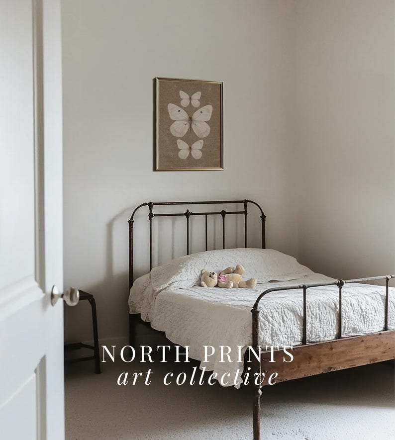 May include: A white metal bed frame with a white linen headboard and a white linen comforter. A stuffed animal is lying on the bed. A framed print of butterflies on a brown background hangs on the wall above the bed. The text "NORTH PRINTS art collective" is printed below the bed.