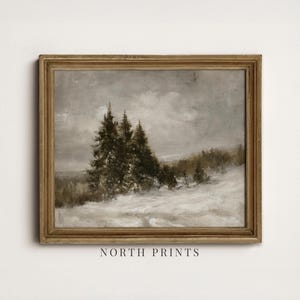 Puede incluir: Un cuadro de paisaje enmarcado que muestra un campo nevado con &aacute;rboles de hoja perenne oscuros bajo un cielo nublado y apagado. La obra est&aacute; en un marco de madera desgastada. El texto NORTH PRINTS aparece en letras may&uacute;sculas negras debajo.