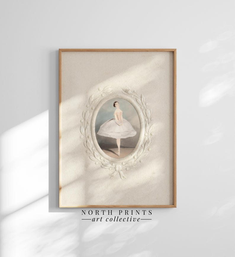 May include: A vintage illustration of a ballerina in a white tutu, framed in a white oval with a decorative floral border. The image is printed on a textured paper and has a light beige background. The frame is made of wood and has a natural finish. The image is titled "NORTH PRINTS - art collective".