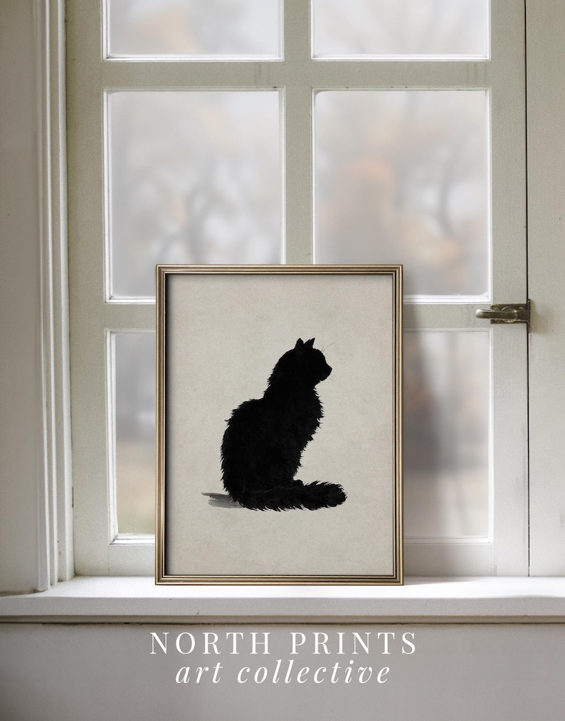 Peut inclure: Une affiche encadr&eacute;e repr&eacute;sentant une silhouette de chat noir. Le chat est assis, la queue enroul&eacute;e. L'affiche est dans un cadre dor&eacute;, expos&eacute;e sur un rebord de fen&ecirc;tre. Le texte "NORTH PRINTS art collective" est en bas.