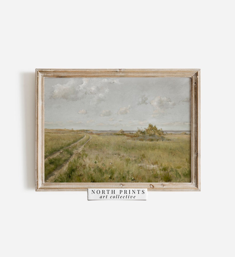 May include: A framed painting of a landscape with a dirt road leading to a body of water. The sky is cloudy and the grass is green. The painting is in a light wood frame. "NORTH PRINTS art collective" is printed on a white label below the frame.