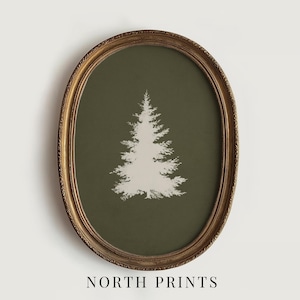 May include: An oval framed print featuring a white pine tree silhouette on a dark olive green background. The frame is gold with ornate detailing. The text "NORTH PRINTS" is at the bottom of the image.