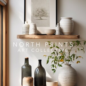 Op de afbeelding: Twee houten planken met verschillende keramische vazen, flessen en kommen. De bovenste plank heeft een ingelijst afdruk van een boom. De onderste plank heeft een plant in een witte vaas. De tekst "NORTH PRINTS ART COLLECTIVE" staat op de planken.