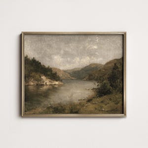 May include: An antique landscape painting in a gold frame. The artwork depicts a serene lake scene surrounded by rolling hills and lush greenery. The color palette is muted, with soft grays, greens, and browns.
