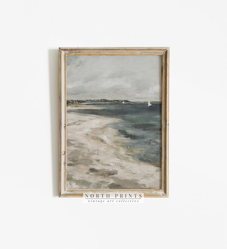 Pu&ograve; includere: Un dipinto incorniciato di un paesaggio marino con una spiaggia sabbiosa, acqua blu e un cielo nuvoloso. Il dipinto &egrave; in una cornice di legno chiaro con una bordura dorata. Il testo "NORTH PRINTS vintage art collective" &egrave; in basso sulla cornice.