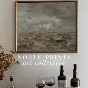 May include: A framed painting of a seascape with a cloudy sky and choppy waves. The painting is hanging on a white wall above a gold tray with two wine glasses, a bottle of wine, and a bottle of liquor. The text "NORTH PRINTS art collective" is printed below the painting.