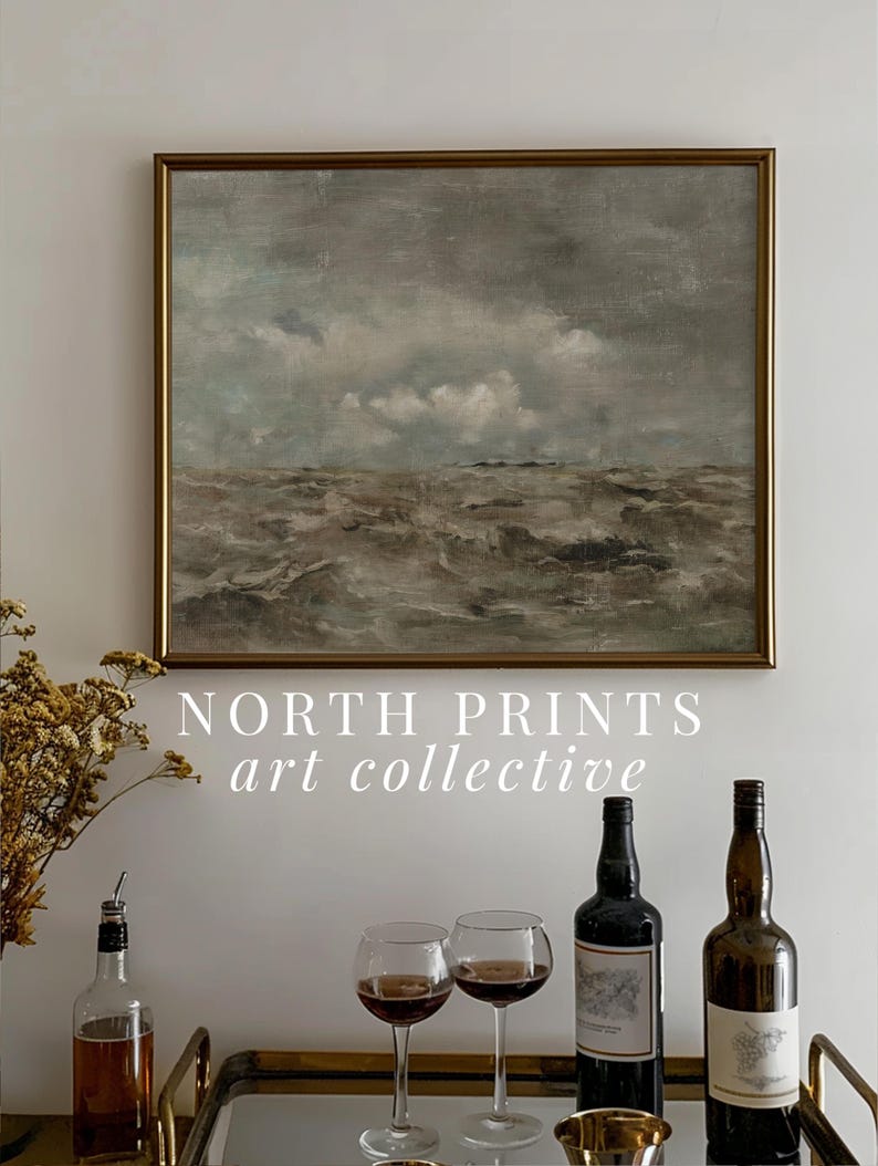 May include: A framed painting of a seascape with a cloudy sky and choppy waves. The painting is hanging on a white wall above a gold tray with two wine glasses, a bottle of wine, and a bottle of liquor. The text "NORTH PRINTS art collective" is printed below the painting.