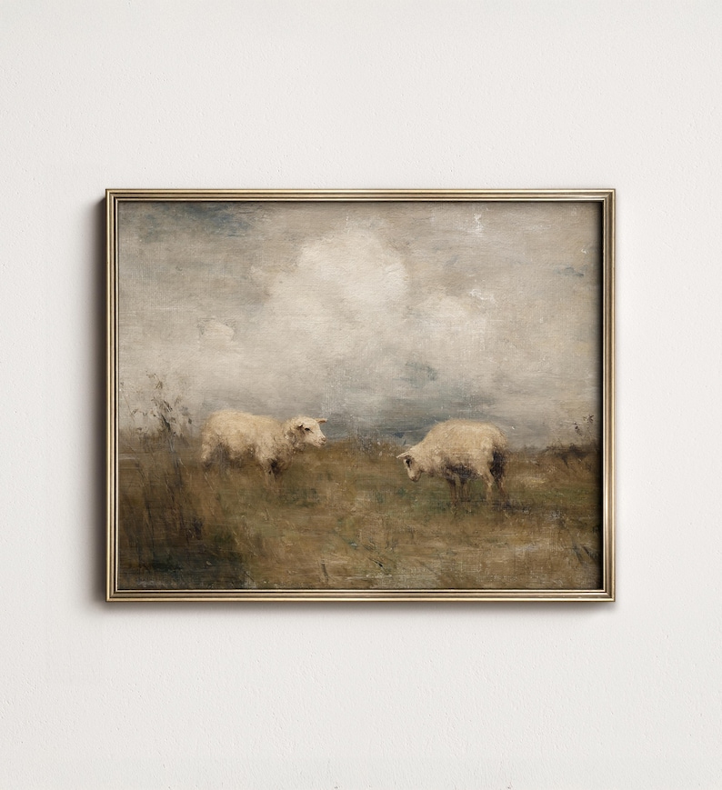 K&ouml;nnte beinhalten: Gerahmtes Gem&auml;lde im Vintage-Stil, das zwei Schafe auf einer Wiese unter einem bew&ouml;lkten Himmel zeigt. Das Kunstwerk verwendet ged&auml;mpfte T&ouml;ne von Braun, Beige und Grau mit einem goldfarbenen Rahmen. Die pastorale Szene vermittelt Ruhe.