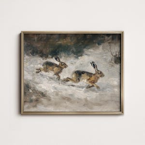 May include: An antique-style framed painting depicts two hares running through a snowy landscape. The hares are brown and tan, with long ears and are in mid-stride. The background features muted tones of brown and gray, suggesting a winter scene.