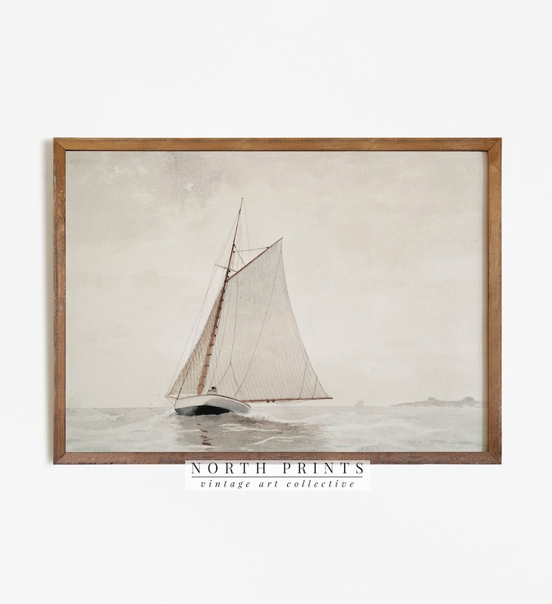May include: A vintage watercolor painting of a sailboat with white sails on a calm sea. The painting is framed in a light brown wood frame. The text "NORTH PRINTS vintage art collective" is at the bottom of the painting.