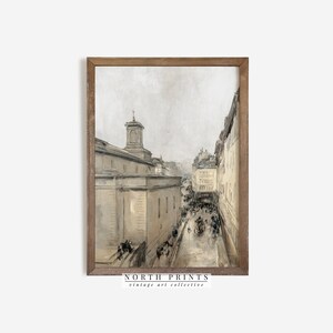 May include: A vintage watercolour painting depicting a street scene in a European city. The painting features a tall building with a steeple, a cobbled street, and people walking along the street. The painting is framed in a wooden frame.