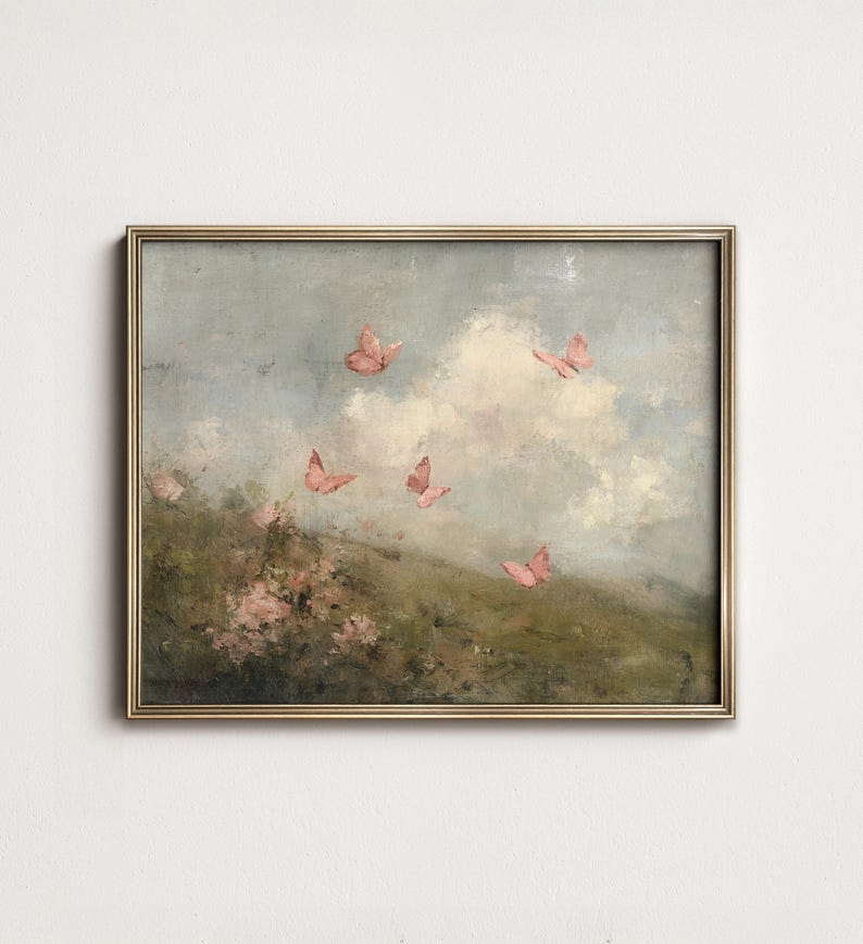 May include: A framed painting featuring a serene landscape with pink butterflies fluttering against a cloudy sky. The artwork has a vintage aesthetic, with soft colors and a gold frame. The scene includes a grassy hill and pink flowers.