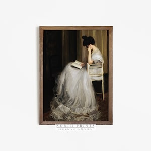 May include: A vintage painting of a woman in a white dress sitting in a chair and reading a book. The painting is framed in a dark wood frame.