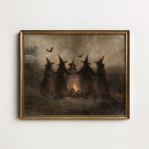 May include: A framed landscape painting in muted brown and gray tones depicting five figures wearing pointed hats standing in a circle around a small, glowing campfire. Two dark silhouettes of bats are visible in the hazy, overcast sky above.