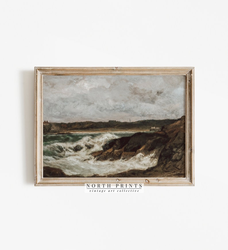 May include: A framed vintage seascape painting depicting a rocky coastline with crashing waves and a cloudy sky. The painting is in a light wood frame and has the text "NORTH PRINTS vintage art collective" at the bottom.