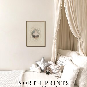 May include: A white canopy bed with a white waffle weave blanket and pillows. The bed has a framed print of a ballerina in a white tutu. The pillows have a variety of patterns, including stars, polka dots, and the text "You are so loved". The text "NORTH PRINTS art collective" is at the bottom of the image.