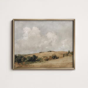 Puede incluir: Pintura de paisaje enmarcada que representa una escena campestre serena. La obra de arte muestra colinas onduladas en tonos de marrón y verde bajo un cielo nublado. El marco es dorado.