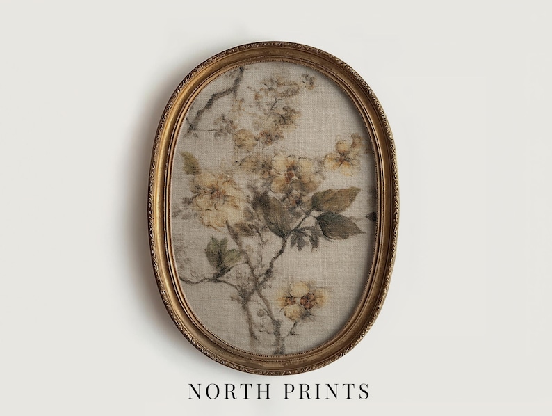 Op de afbeelding: Een ovaalvormige ingelijste print met een botanisch bloemenontwerp. Het kunstwerk toont een gedempt kleurenpalet met beige, gele en groene tinten. De lijst is goudkleurig met ingewikkelde details. De tekst "NORTH PRINTS" staat onderaan.
