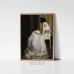 May include: A vintage painting of a woman in a white dress sitting in a chair and reading a book. The painting is framed in a gold frame.