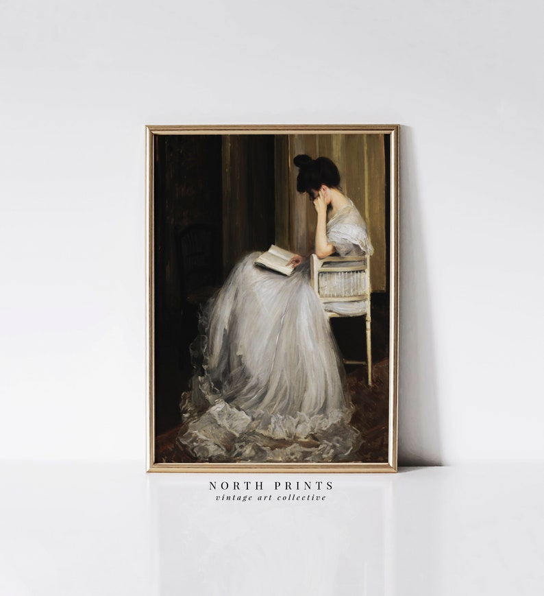 May include: A vintage painting of a woman in a white dress sitting in a chair and reading a book. The painting is framed in a gold frame.