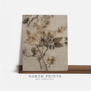 Op de afbeelding: Een bloemenprint op canvas met een beige achtergrond en een botanisch ontwerp in bruin- en geeltinten. Het kunstwerk wordt gepresenteerd op een houten plank. De tekst "NORTH PRINTS art collective" staat onderaan.