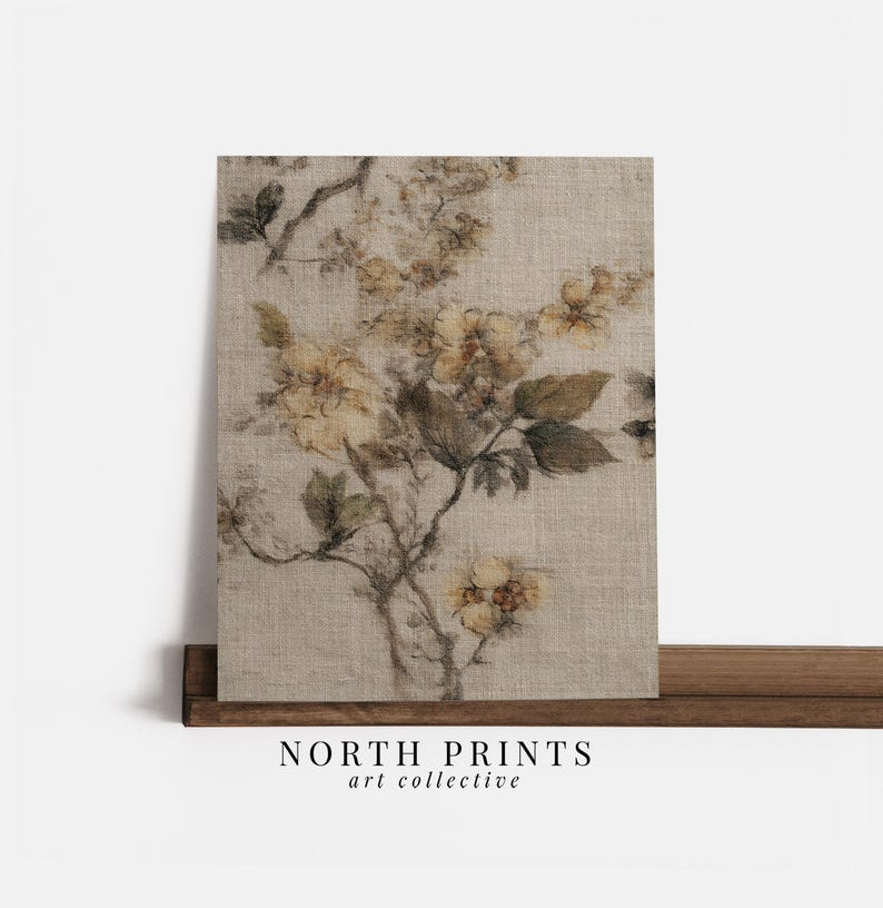 Op de afbeelding: Een bloemenprint op canvas met een beige achtergrond en een botanisch ontwerp in bruin- en geeltinten. Het kunstwerk wordt gepresenteerd op een houten plank. De tekst "NORTH PRINTS art collective" staat onderaan.