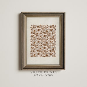 May include: A framed print featuring a brown floral pattern on a white background. The frame is a light brown wood with a gold trim. The print is titled "NORTH PRINTS art collective".