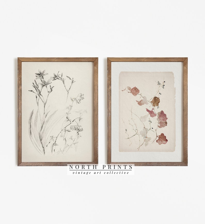 May include: Two framed botanical prints, one with a black and white drawing of a flower and the other with a watercolor painting of leaves in shades of pink and brown. The frames are wood with a light brown finish. The prints are titled "NORTH PRINTS vintage art collective".
