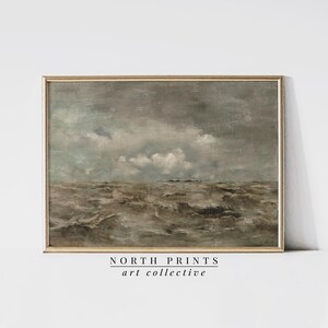 May include: A framed painting of a seascape with a stormy sky and choppy waves. The sky is a muted gray with white clouds. The waves are a dark brown and gray.