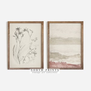 May include: Two framed prints, one with a black and white botanical illustration of flowers and leaves, and the other with a watercolor-style landscape in shades of brown and pink. The frames are a light brown wood.