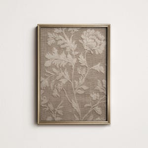 Può includere: Stampa botanica incorniciata con un design floreale color crema su sfondo beige. L'opera d'arte è racchiusa in una cornice dorata, creando un'estetica classica ed elegante. La stampa presenta un effetto strutturato e in rilievo.