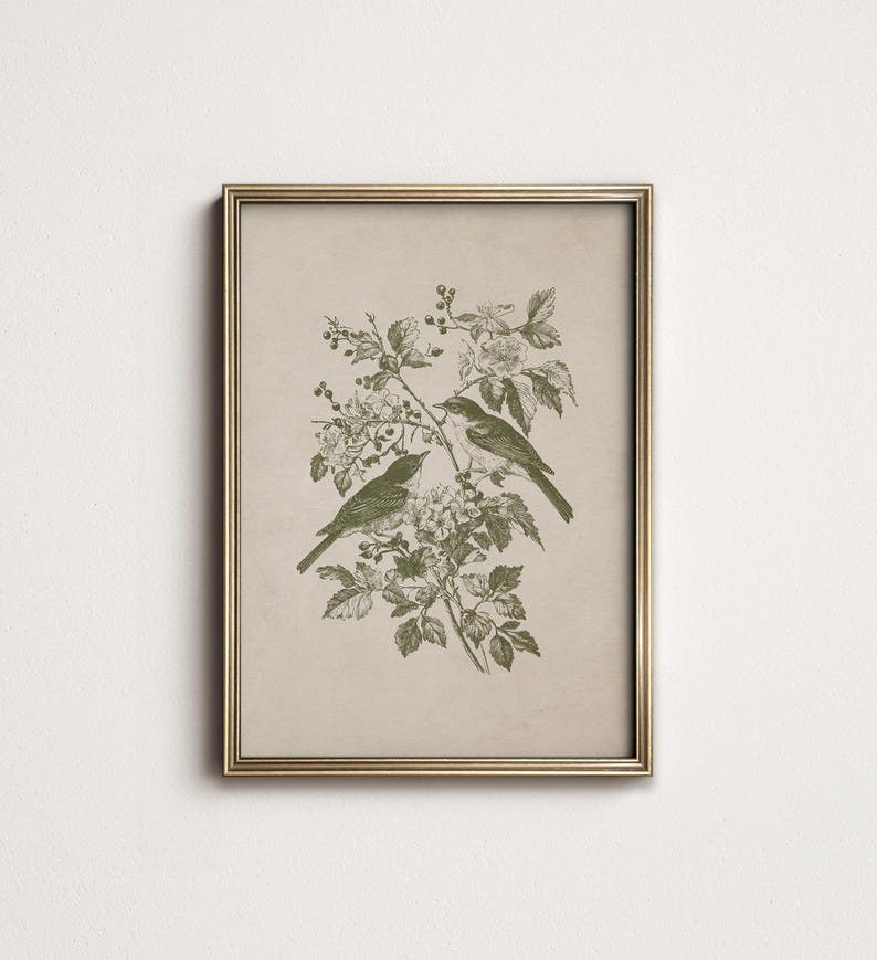 May include: Framed botanical print featuring two birds perched on a flowering branch. The artwork is rendered in shades of green on a beige background, encased in a gold-colored frame. A classic nature-themed wall art piece.