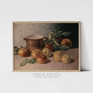 May include: A vintage still life painting of a brown ceramic pitcher and a group of apples on a table. The apples are various shades of red, yellow, and green. The painting is framed in a gold frame.