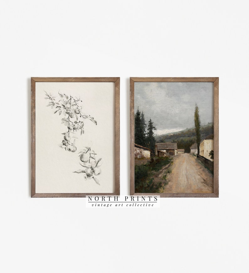 May include: Two framed vintage art prints. One features a black and white botanical illustration of hanging fruit. The other is a landscape painting of a road leading to buildings under a cloudy sky. The frames are made of wood. The text "NORTH PRINTS vintage art collective" is at the bottom.