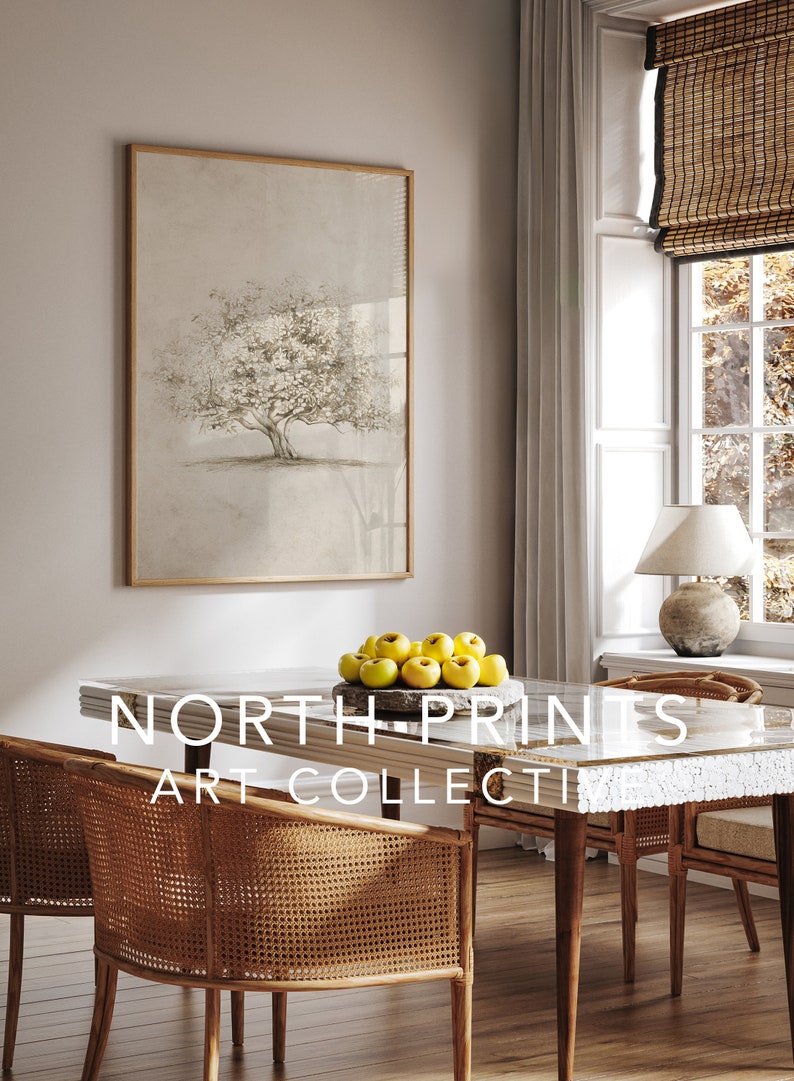 Op de afbeelding: Een ingelijste print van een boom met een lichtbruine achtergrond. De print hangt aan een muur in een eetkamer met een houten tafel en stoelen. Op de tafel staat een kom met gele appels. De tekst "NORTH PRINTS ART COLLECTI" is zichtbaar op de tafel.