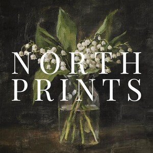 May include: A bouquet of white lily of the valley flowers in a clear glass vase with a dark background. The text "NORTH PRINTS" is displayed in white letters.