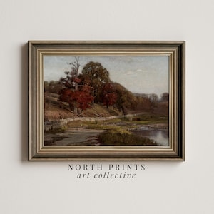 May include: A framed landscape painting depicting a river flowing through a forest with trees in various shades of green and red. The painting is set in a rustic wooden frame with a gold trim.