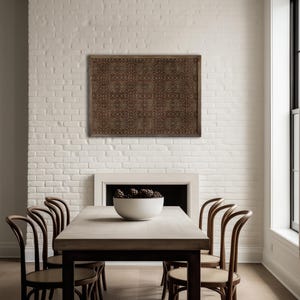 May include: A dining room with a wooden table and six chairs. A patterned artwork hangs on the white brick wall above a fireplace. A white bowl with pinecones sits on the table. The room has a minimalist design.