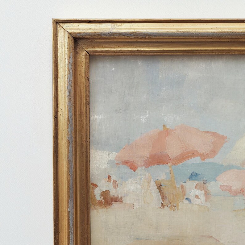 Puede incluir: Pintura al &oacute;leo enmarcada que representa una escena de playa. Una sombrilla rosa proporciona sombra en la playa de arena bajo un cielo azul claro. Se ven figuras en la playa. La obra evoca un d&iacute;a soleado junto al mar.