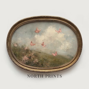 May include: An oval-shaped framed painting featuring a pastoral scene with pink butterflies fluttering in a cloudy sky. The artwork has a vintage aesthetic, with a gold-colored ornate frame. The text "NORTH PRINTS" is printed at the bottom of the frame.