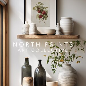 Peut inclure: Pr&eacute;sentation d'objets d&eacute;coratifs sur des &eacute;tag&egrave;res en bois. Une impression encadr&eacute;e de pommes rouges est suspendue au-dessus de divers vases en c&eacute;ramique, bols et bouteilles en verre. Le texte "NORTH PRINTS ART COLLECTIVE" est visible.