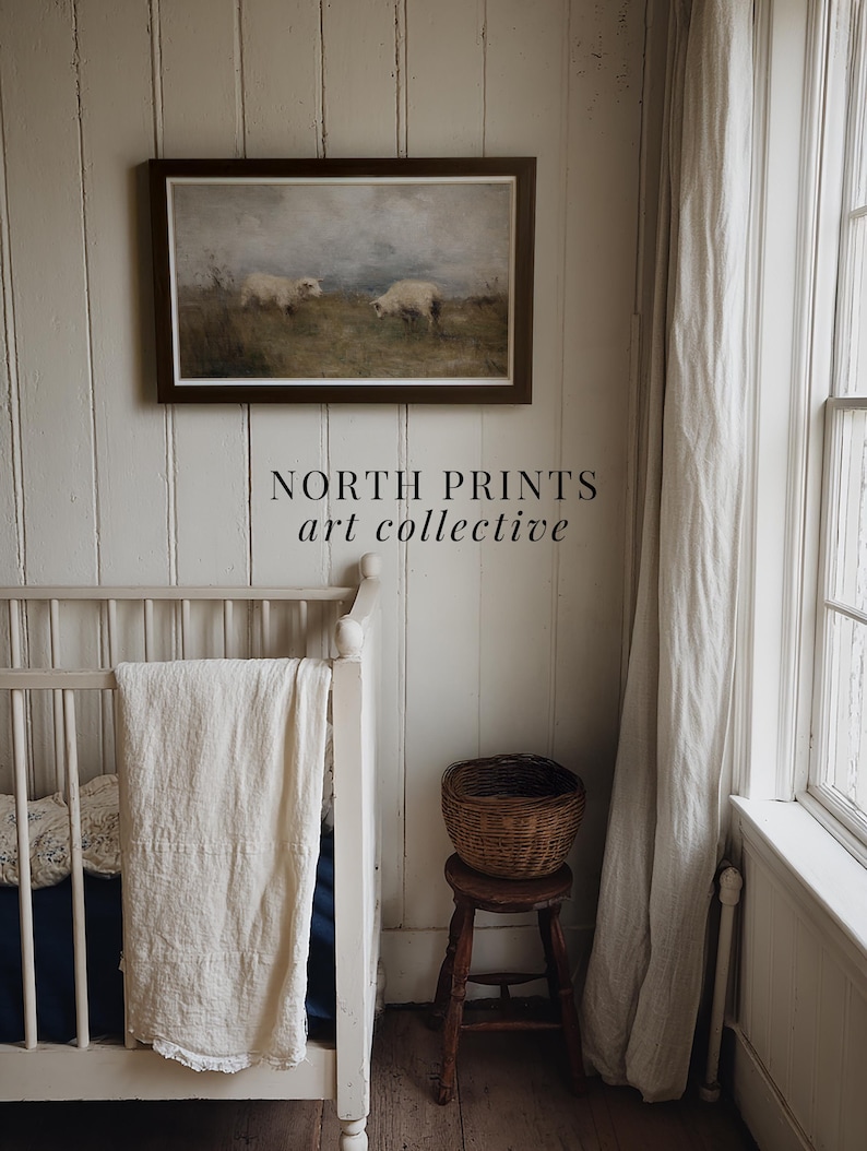 K&ouml;nnte beinhalten: Gerahmtes Landschaftsgem&auml;lde mit zwei Schafen auf einem Feld &uuml;ber einem wei&szlig;en Kinderbett. Ein kleiner Holzschemel tr&auml;gt einen Weidenkorb. Der Text "NORTH PRINTS art collective" ist darunter.