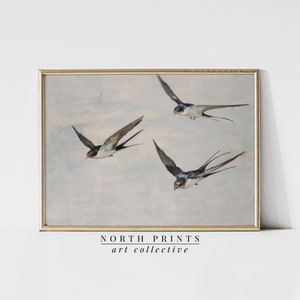 May include: A vintage-style painting of three swallows in flight against a light blue sky. The swallows are painted in shades of brown, black, and white. The painting is framed in a gold frame.