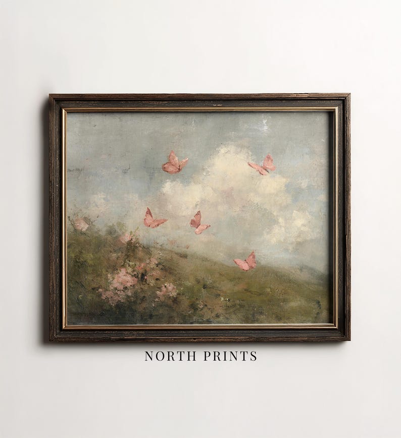 May include: Framed vintage-style artwork featuring a pastoral scene with pink butterflies fluttering against a cloudy sky. The painting has a dark brown wooden frame and the text "NORTH PRINTS" at the bottom.