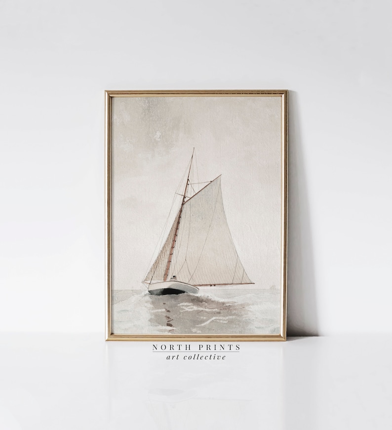 Puede incluir: Una pintura de acuarela enmarcada de un velero con velas blancas sobre un fondo azul claro y gris. El velero navega en una masa de agua con olas. La pintura est&aacute; enmarcada en un marco dorado. El texto "NORTH PRINTS art collective" est&aacute; impreso debajo de la imagen.