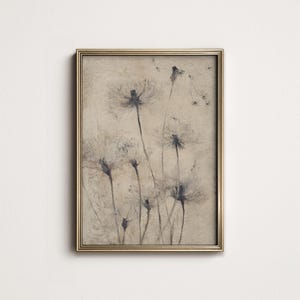 以下が含まれることがあります： タンポポのセピア色の画像が特徴の額入りプリント。タンポポは、繊細なディテールで、柔らかく絵画的なスタイルで描かれています。フレームは薄い金色の金属です。