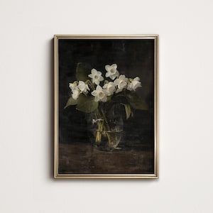 May include: A framed painting of a bouquet of white flowers in a clear glass vase. The flowers are arranged in a simple, elegant way, and the background is a dark, moody color.